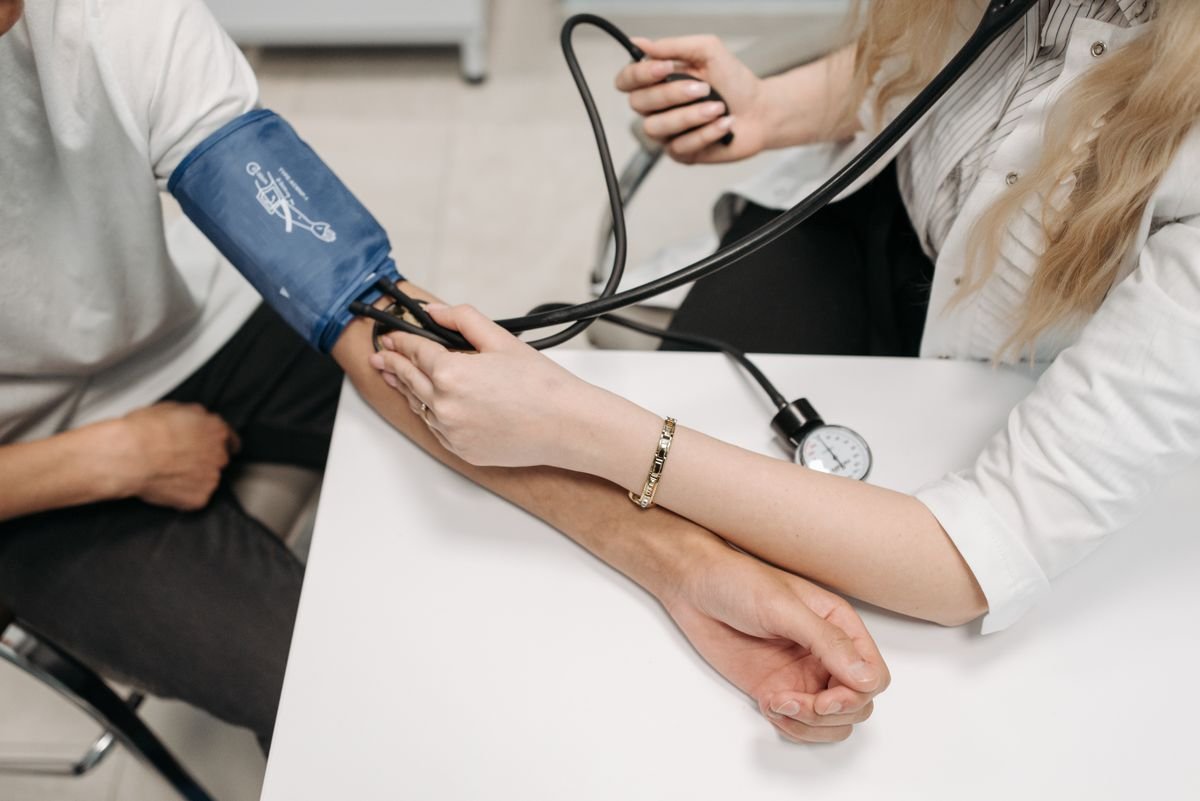 A doctor checking a middle-aged man's blood pressure at a clinic