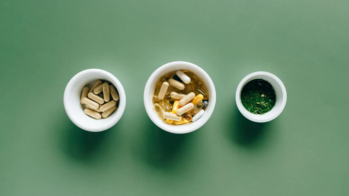 Three small bowls holding different supplement capsules and herbs, side by side